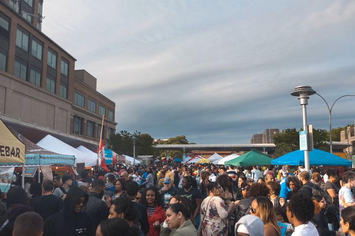 The crowd at Bronx Night Market at dusk, vendor tents down both sides.